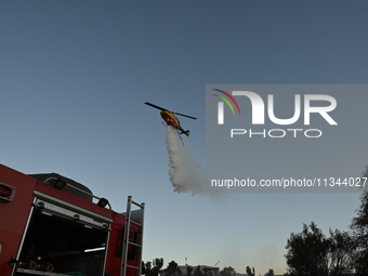 A firefighting helicopter is dropping water to extinguish a wildfire in Koropi near Athens, Greece, on June 19, 2024. (