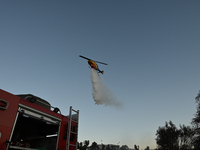 A firefighting helicopter is dropping water to extinguish a wildfire in Koropi near Athens, Greece, on June 19, 2024. (