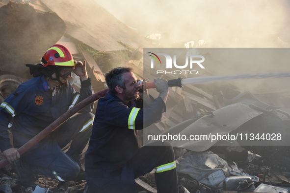 Firefighters are dropping water to extinguish a fire inside a container in Koropi near Athens, Greece, on June 19, 2024. 