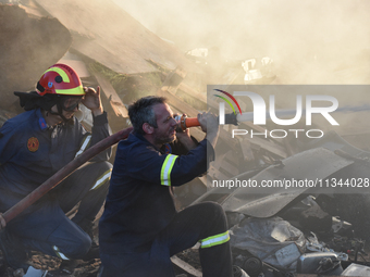 Firefighters are dropping water to extinguish a fire inside a container in Koropi near Athens, Greece, on June 19, 2024. (