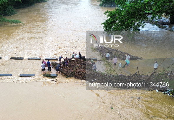 Villagers are braving the rain to clean branches stuck on a bridge in Banlan township, Rongan County, Liuzhou city, South China's Guangxi Zh...