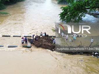 Villagers are braving the rain to clean branches stuck on a bridge in Banlan township, Rongan County, Liuzhou city, South China's Guangxi Zh...