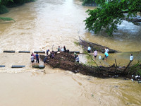 Villagers are braving the rain to clean branches stuck on a bridge in Banlan township, Rongan County, Liuzhou city, South China's Guangxi Zh...