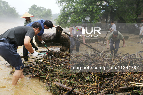 Villagers are braving the rain to clean branches stuck on a bridge in Banlan township, Rongan County, Liuzhou city, South China's Guangxi Zh...