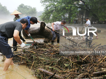 Villagers are braving the rain to clean branches stuck on a bridge in Banlan township, Rongan County, Liuzhou city, South China's Guangxi Zh...