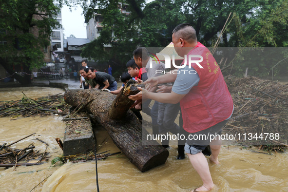 Villagers are braving the rain to clean branches stuck on a bridge in Banlan township, Rongan County, Liuzhou city, South China's Guangxi Zh...