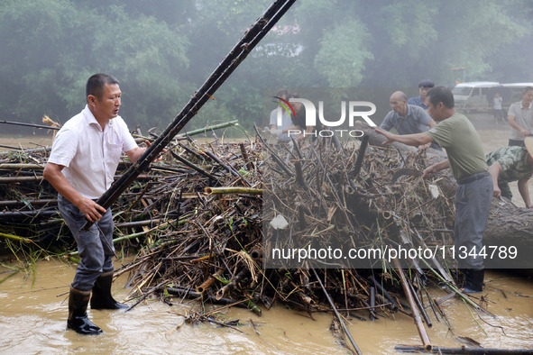 Villagers are braving the rain to clean branches stuck on a bridge in Banlan township, Rongan County, Liuzhou city, South China's Guangxi Zh...