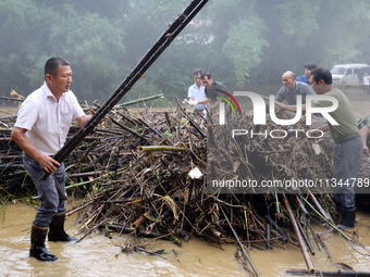 Villagers are braving the rain to clean branches stuck on a bridge in Banlan township, Rongan County, Liuzhou city, South China's Guangxi Zh...