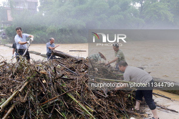 Villagers are braving the rain to clean branches stuck on a bridge in Banlan township, Rongan County, Liuzhou city, South China's Guangxi Zh...