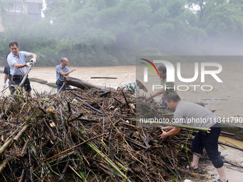 Villagers are braving the rain to clean branches stuck on a bridge in Banlan township, Rongan County, Liuzhou city, South China's Guangxi Zh...