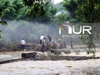 Villagers are braving the rain to clean branches stuck on a bridge in Banlan township, Rongan County, Liuzhou city, South China's Guangxi Zh...