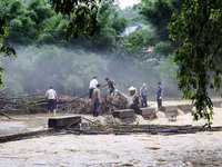 Villagers are braving the rain to clean branches stuck on a bridge in Banlan township, Rongan County, Liuzhou city, South China's Guangxi Zh...