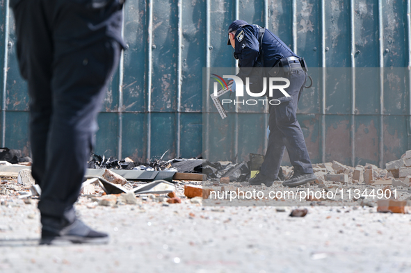 A police officer is examining the site where the fragments of a Russian kamikaze drone landed near the destroyed administrative building of...