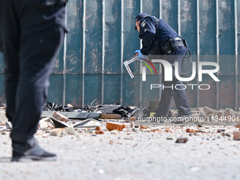 A police officer is examining the site where the fragments of a Russian kamikaze drone landed near the destroyed administrative building of...