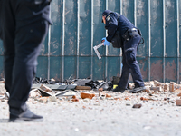 A police officer is examining the site where the fragments of a Russian kamikaze drone landed near the destroyed administrative building of...