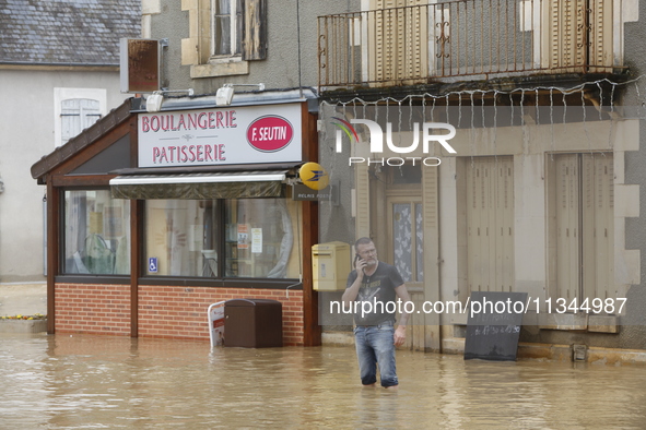 A man is standing in front of his bakery after rising waters in Narcy, France, on June 20, 2024. 