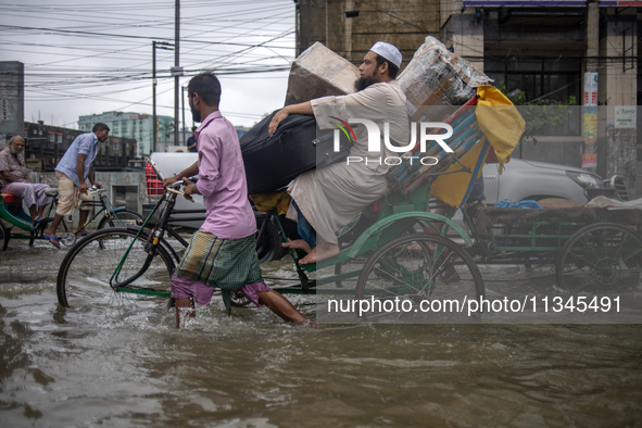 People are moving through a flooded street in Sylhet city, Sylhet, Bangladesh, on Thursday, June 20, 2024. In Sylhet, lashing rain and river...