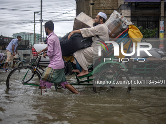 People are moving through a flooded street in Sylhet city, Sylhet, Bangladesh, on Thursday, June 20, 2024. In Sylhet, lashing rain and river...