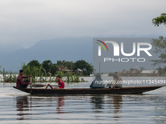 People are moving through flooded water as they are riding on a boat in Companiganj, Sylhet, Bangladesh, on Thursday, June 20, 2024. In Sylh...