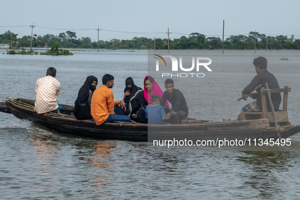 People are moving through flooded water as they are riding on a boat in Companiganj, Sylhet, Bangladesh, on Thursday, June 20, 2024. In Sylh...