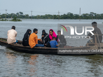 People are moving through flooded water as they are riding on a boat in Companiganj, Sylhet, Bangladesh, on Thursday, June 20, 2024. In Sylh...