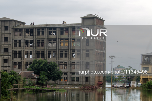 People are sitting on top of a building being used as a shelter for flood-affected people in Companiganj, Sylhet, Bangladesh, on Thursday, J...