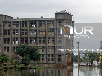 People are sitting on top of a building being used as a shelter for flood-affected people in Companiganj, Sylhet, Bangladesh, on Thursday, J...