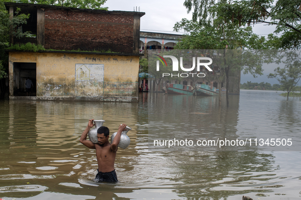 A man is carrying drinking water towards his home in Companiganj, Sylhet, Bangladesh, on June 20, 2024. In Sylhet, lashing rain and rivers s...