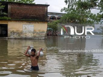 A man is carrying drinking water towards his home in Companiganj, Sylhet, Bangladesh, on June 20, 2024. In Sylhet, lashing rain and rivers s...