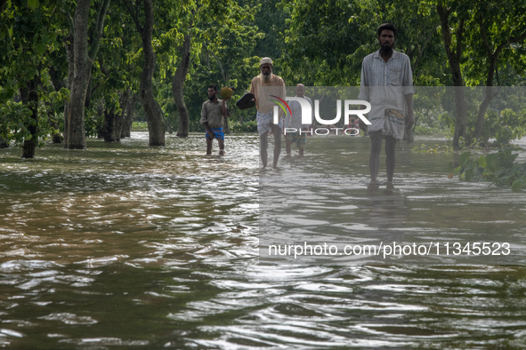 People are wading through a flooded street in Companiganj, Sylhet, Bangladesh, on June 20, 2024. In Sylhet, lashing rain and rivers swollen...