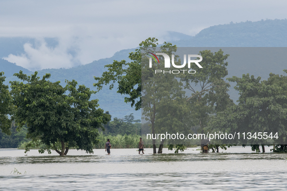 People are wading through a flooded street in Companiganj, Sylhet, Bangladesh, on June 20, 2024. In Sylhet, lashing rain and rivers swollen...