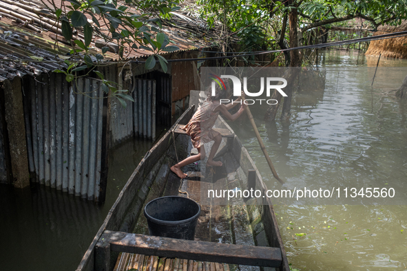 A girl is riding a boat as she passes partially submerged houses in flood waters in Companiganj, Sylhet, Bangladesh, on June 20, 2024. In Sy...