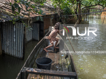 A girl is riding a boat as she passes partially submerged houses in flood waters in Companiganj, Sylhet, Bangladesh, on June 20, 2024. In Sy...