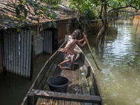 A girl is riding a boat as she passes partially submerged houses in flood waters in Companiganj, Sylhet, Bangladesh, on June 20, 2024. In Sy...