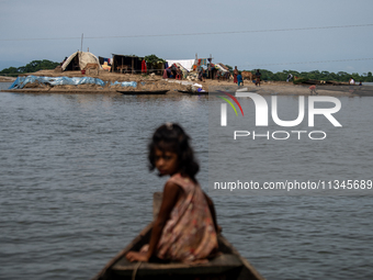 A child is reacting to the camera as she is moving towards temporary shelter in an elevated space during flooding in Companiganj, Sylhet, Ba...