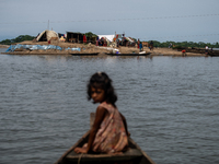 A child is reacting to the camera as she is moving towards temporary shelter in an elevated space during flooding in Companiganj, Sylhet, Ba...