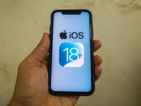 The Apple logo is seen with the iOS 18 operating system logo on a mobile device in this illustration photo taken in L’Aquila, Italy, on June...