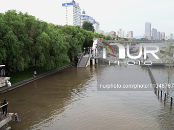 Part of the pedestrian walkway is being submerged by the rising waters of the Sandao pier along the Songhua River in Jilin City, Jilin provi...