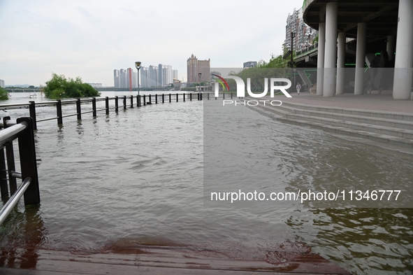 Part of the pedestrian walkway is being submerged by the rising waters of the Sandao pier along the Songhua River in Jilin City, Jilin provi...