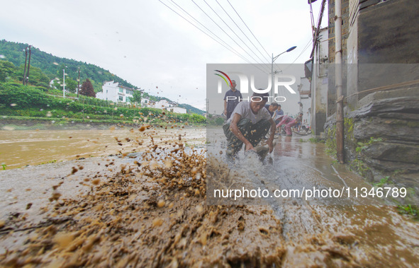 Villagers are cleaning up silt at Changjing Village in Qiukou, Wuyuan county, Shangrao city, East China's Jiangxi province, on June 20, 2024...