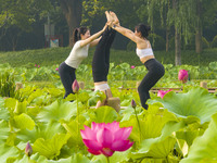 Yoga lovers are practicing yoga on the lotus pond trestle at Tiande Lake Park in Taizhou, China, on June 21, 2024. (