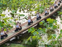 Yoga lovers are practicing yoga on the lotus pond trestle at Tiande Lake Park in Taizhou, China, on June 21, 2024. (