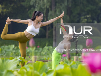 Yoga lovers are practicing yoga on the lotus pond trestle at Tiande Lake Park in Taizhou, China, on June 21, 2024. (