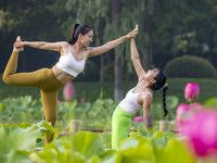 Yoga lovers are practicing yoga on the lotus pond trestle at Tiande Lake Park in Taizhou, China, on June 21, 2024. (