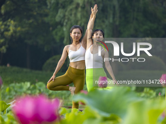 Yoga lovers are practicing yoga on the lotus pond trestle at Tiande Lake Park in Taizhou, China, on June 21, 2024. (