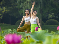 Yoga lovers are practicing yoga on the lotus pond trestle at Tiande Lake Park in Taizhou, China, on June 21, 2024. (