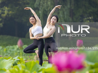 Yoga lovers are practicing yoga on the lotus pond trestle at Tiande Lake Park in Taizhou, China, on June 21, 2024. (