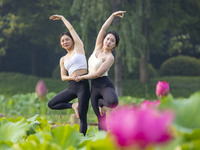 Yoga lovers are practicing yoga on the lotus pond trestle at Tiande Lake Park in Taizhou, China, on June 21, 2024. (