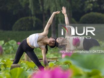 Yoga lovers are practicing yoga on the lotus pond trestle at Tiande Lake Park in Taizhou, China, on June 21, 2024. (