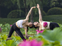 Yoga lovers are practicing yoga on the lotus pond trestle at Tiande Lake Park in Taizhou, China, on June 21, 2024. (